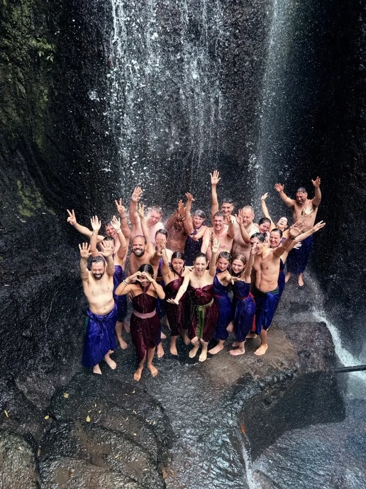 Dancers lying in a circle on the rocks by a waterfall, seen from above
